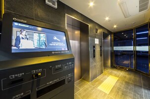Un ascensor con pantalla digital y un cartel que indica que es el vestíbulo del Hotel IDP Press.