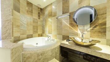 A modern bathroom with a freestanding bathtub, a round mirror, and a vessel sink.