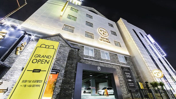 Un hotel de diseño moderno, con un cartel llamativo que dice 'HOTEL' y un banner que anuncia 'GRAN APERTURA'.