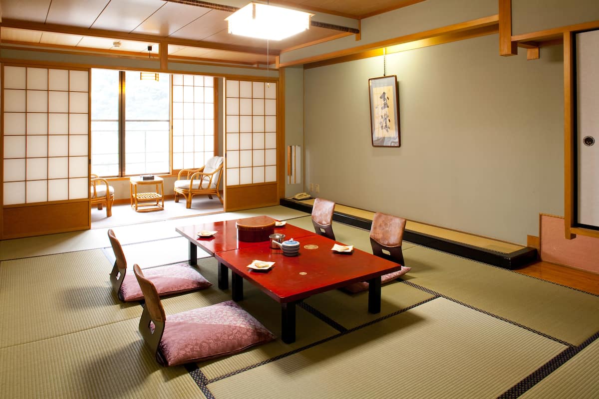 A traditional Japanese room with tatami flooring, a low table with cushions, and sliding doors.