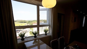 A dining area with a table, chairs, a window with a view of a green landscape, and a hanging light fixture. - May AVE (Yeoju)