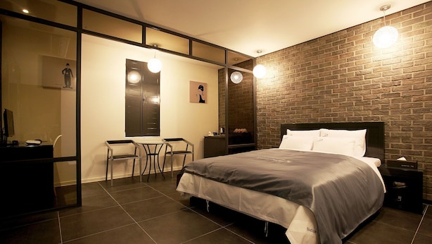 A modern bedroom with a large bed, a desk, and a chair. - May AVE (Yeoju)