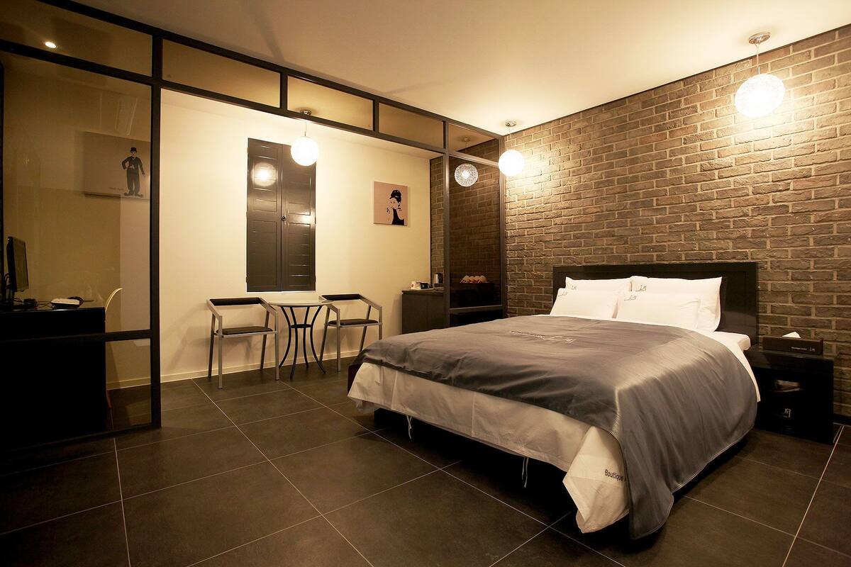 A modern bedroom with a large bed, a desk, and a chair.