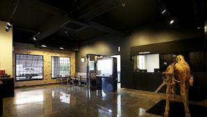 A spacious lobby with a polished floor, a seating area with chairs, a vending machine, and a large sculpture. - May AVE (Yeoju)