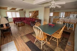 A spacious living area with a large dining table, wooden chairs, a red sofa, and a staircase leading to another level. - Avon Cottages (Avon)