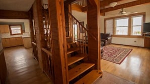 A spacious living area with a wooden staircase, a kitchen with wooden cabinets, and a large window providing natural light. - Avon Cottages (Avon)