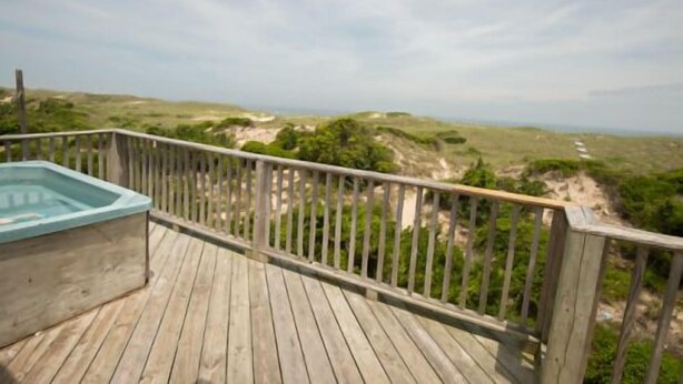 A wooden deck with a hot tub and a view of a coastal landscape. - Avon Cottages (Avon)