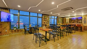 A modern restaurant with wooden floors, large windows, and a bar area. - Lavender Riverside Hotel (Da Nang)