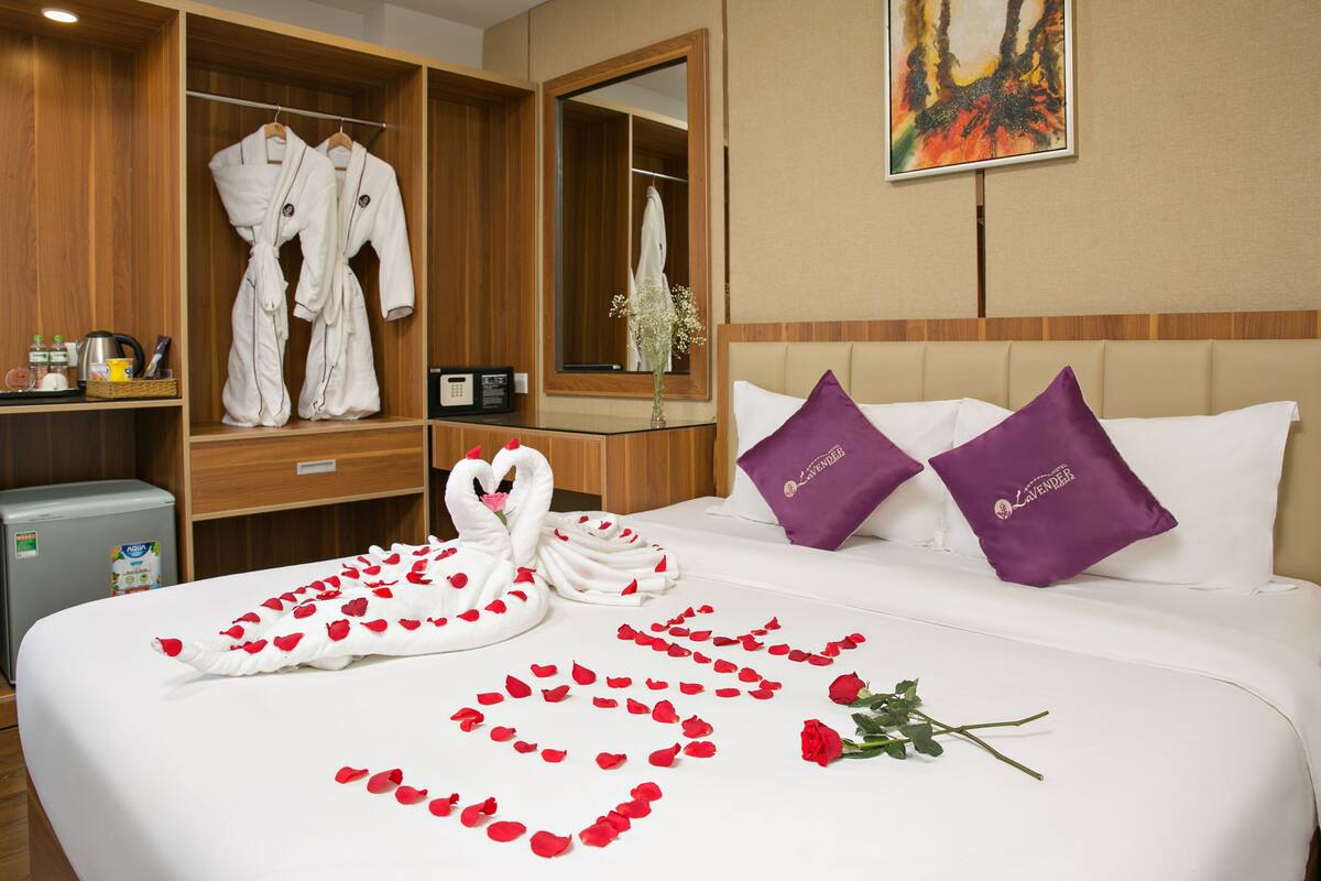 A hotel room with a neatly made bed, a robe rack, and a minibar.