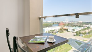 A balcony with a table, a chair, a cup, and a magazine. - Lavender Riverside Hotel (Da Nang)