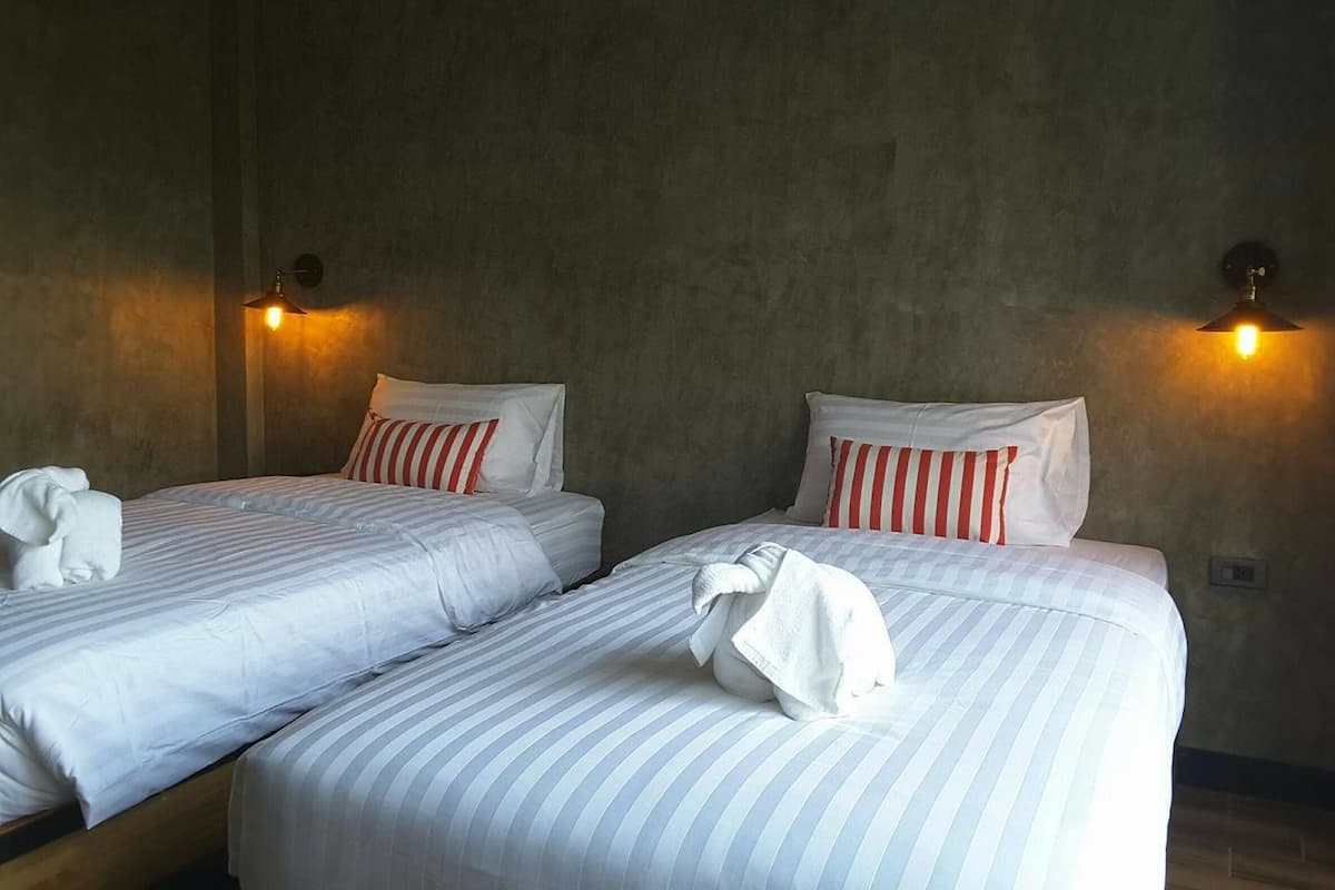 Two single beds with striped bedding, a towel on each bed, and wall-mounted lamps.