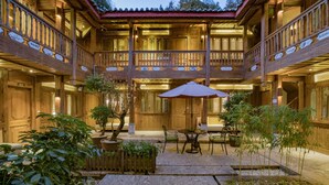 A traditional wooden building with multiple balconies, a central courtyard with a table and chairs, and potted plants. - Ivy Garden Hotels & Resorts - Lijiang Henghehao (Lijiang)