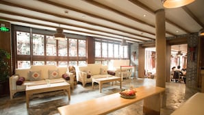 A spacious lobby with a stone floor, wooden benches, and sofas with cushions. - Ivy Garden Hotels & Resorts - Lijiang Henghehao (Lijiang)
