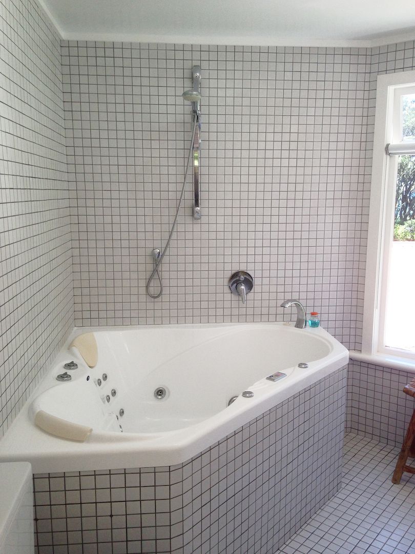 Ein Badezimmer mit einer großen Badewanne, einer Duschbrause und einem Fenster.
