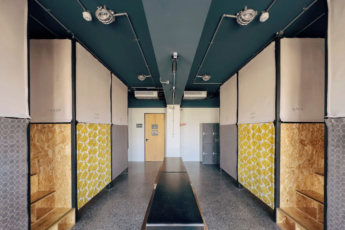 A hallway with lockers, a wooden door, and a metal bench.
