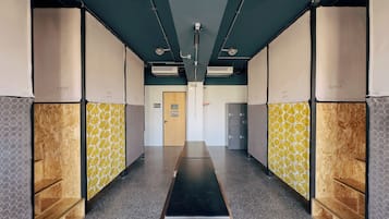 A hallway with lockers, a wooden door, and a metal bench.