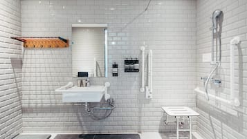 A modern bathroom with white tiled walls, a sink, a mirror, and a shower.