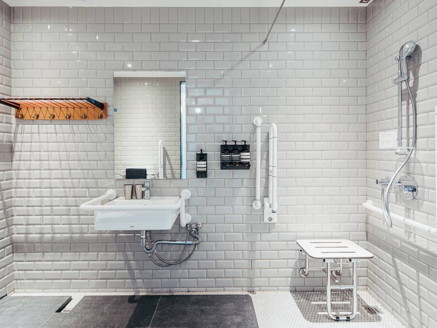 A modern bathroom with white tiled walls, a sink, a mirror, and a shower.