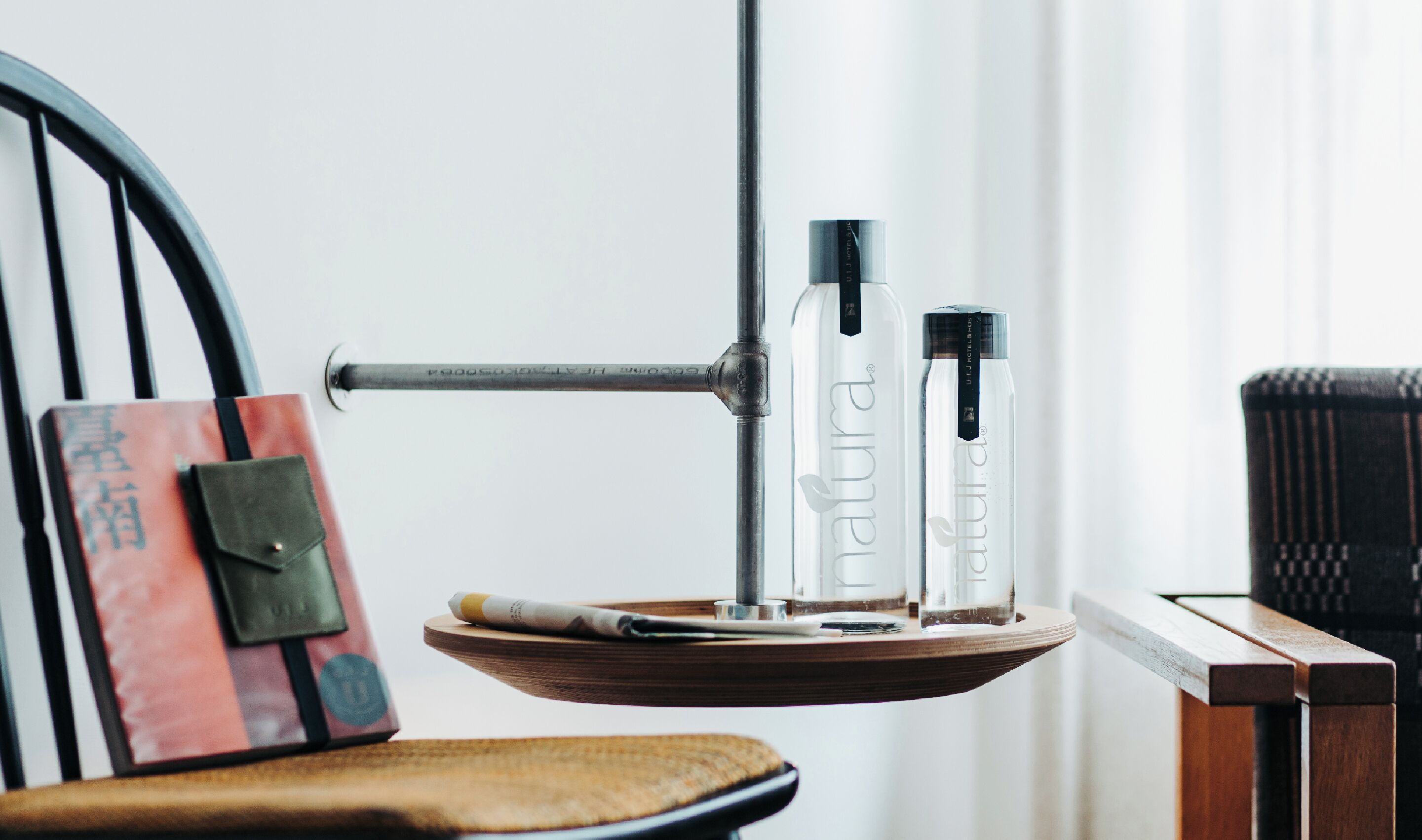 A wooden tray with two bottles of water and a cigarette pack on a chair.