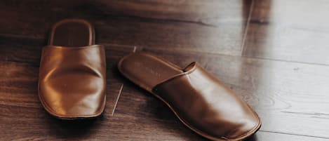 Un par de pantuflas de cuero marrón sobre un piso de madera.