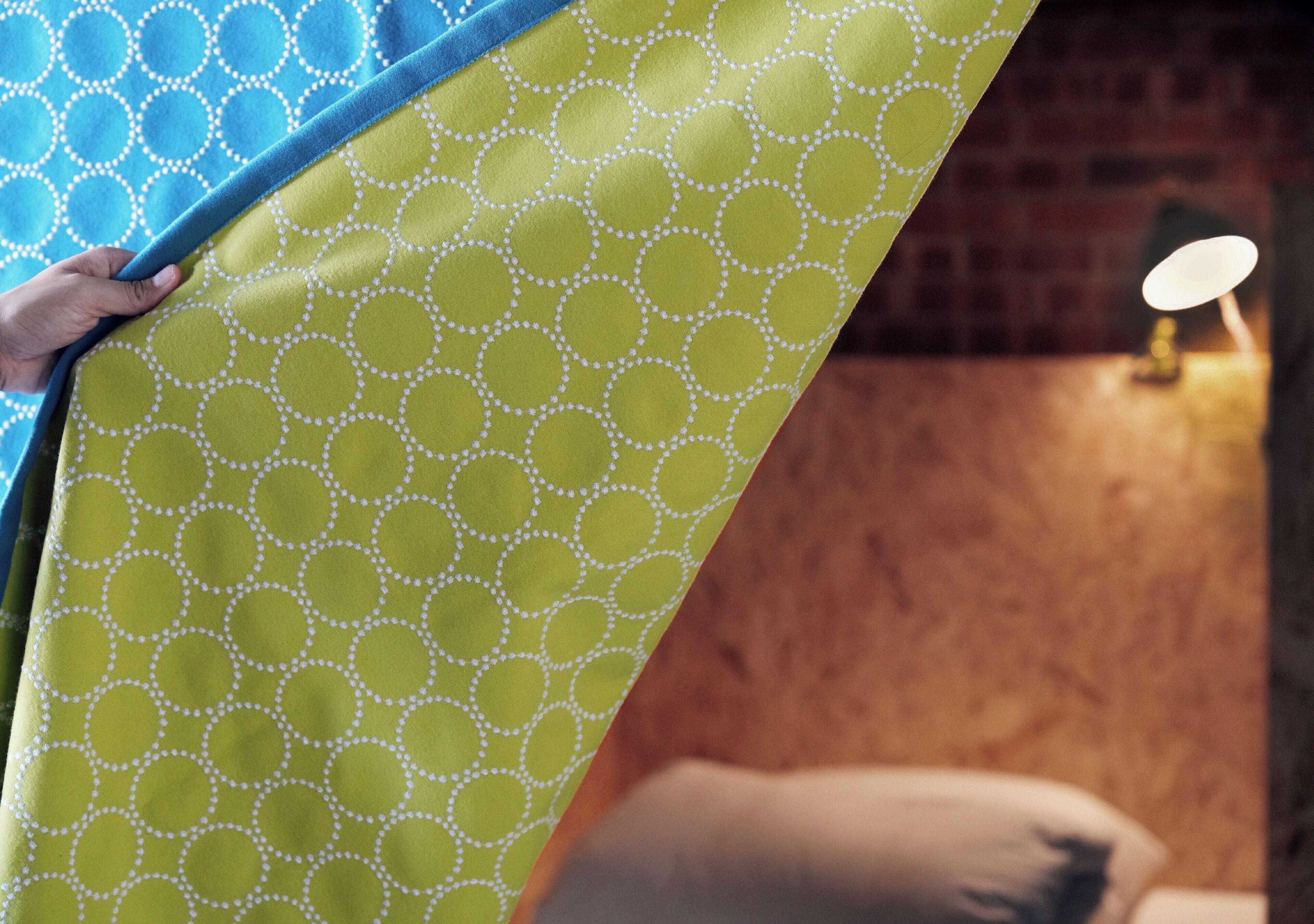 A person holding a patterned blanket with a geometric design.
