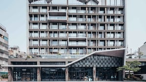 Un edificio moderno de varios pisos con una entrada curva destacada y varios balcones.