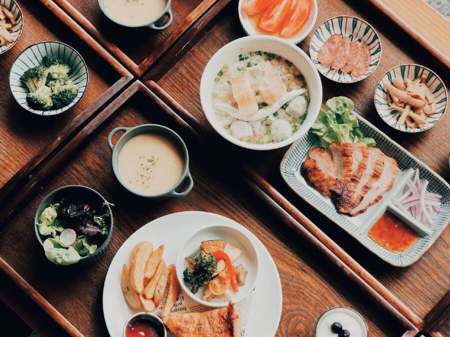 Ein Holztisch mit verschiedenen Speisen, darunter Sushi, Sashimi und eine Suppenschüssel.