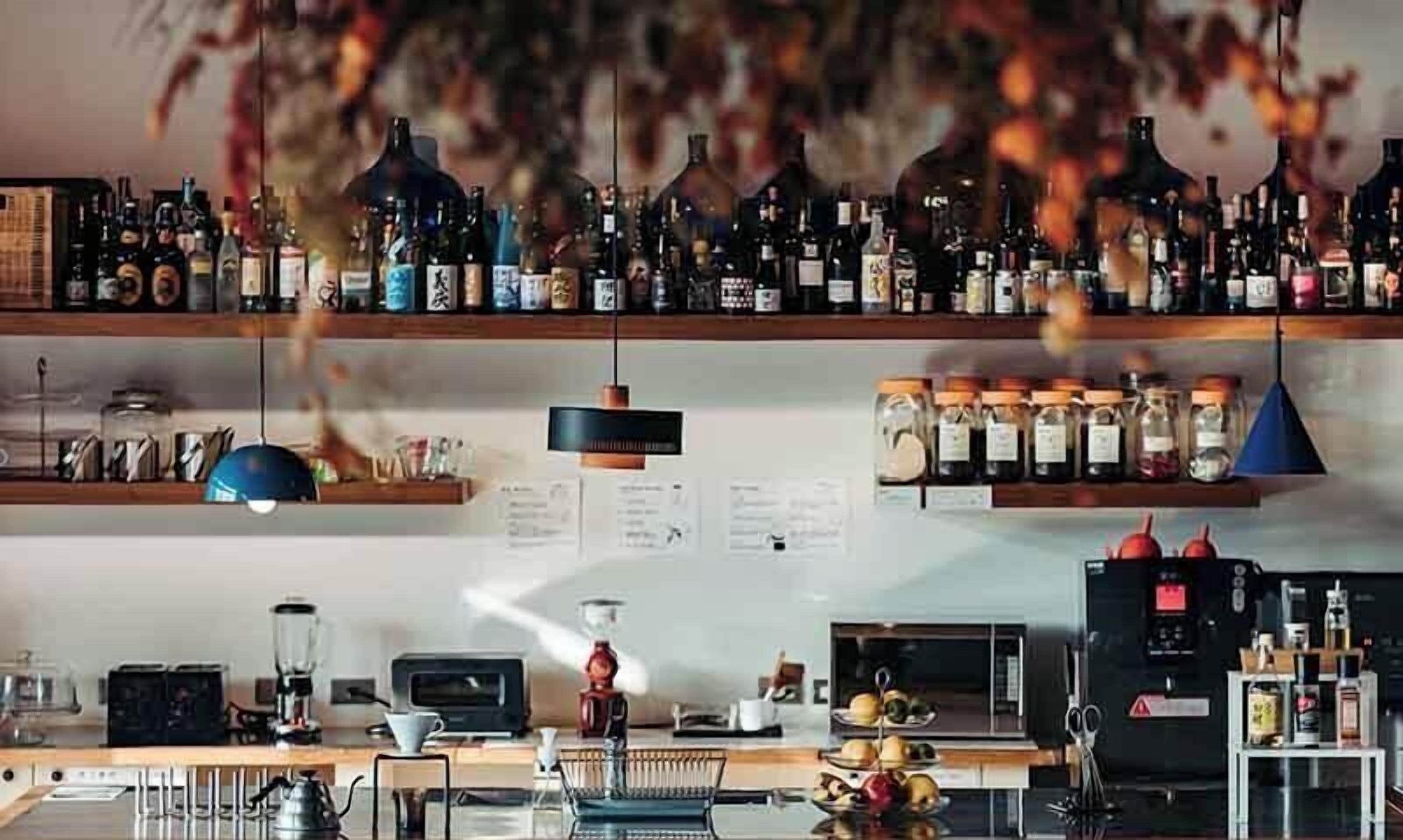 A bar area with shelves of bottles, a coffee machine, and a microwave.