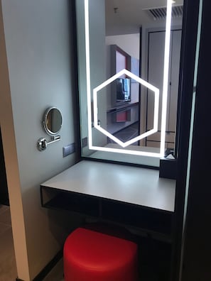 A modern bathroom with a vanity, a round mirror, and a red stool. - theRED (Kuala Lumpur)