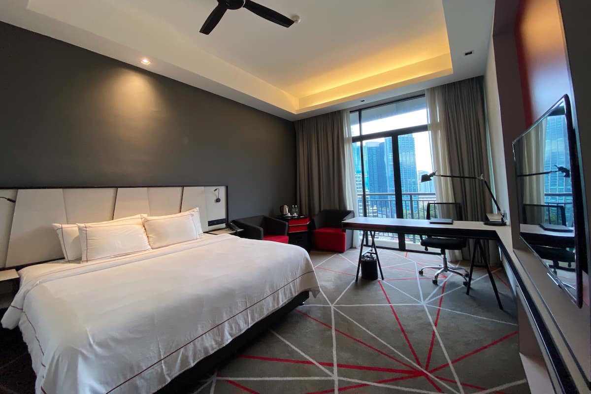 Habitación de hotel con una cama grande, un escritorio, una silla y vistas a la ciudad.