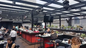 An indoor dining area with tables and chairs, a bar area with a red counter, and potted plants on shelves. - theRED (Kuala Lumpur)