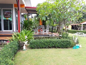 A well-maintained garden with a wooden deck, seating area, and decorative statues. - Ban Lek Resort (Prachuap Khiri Khan)