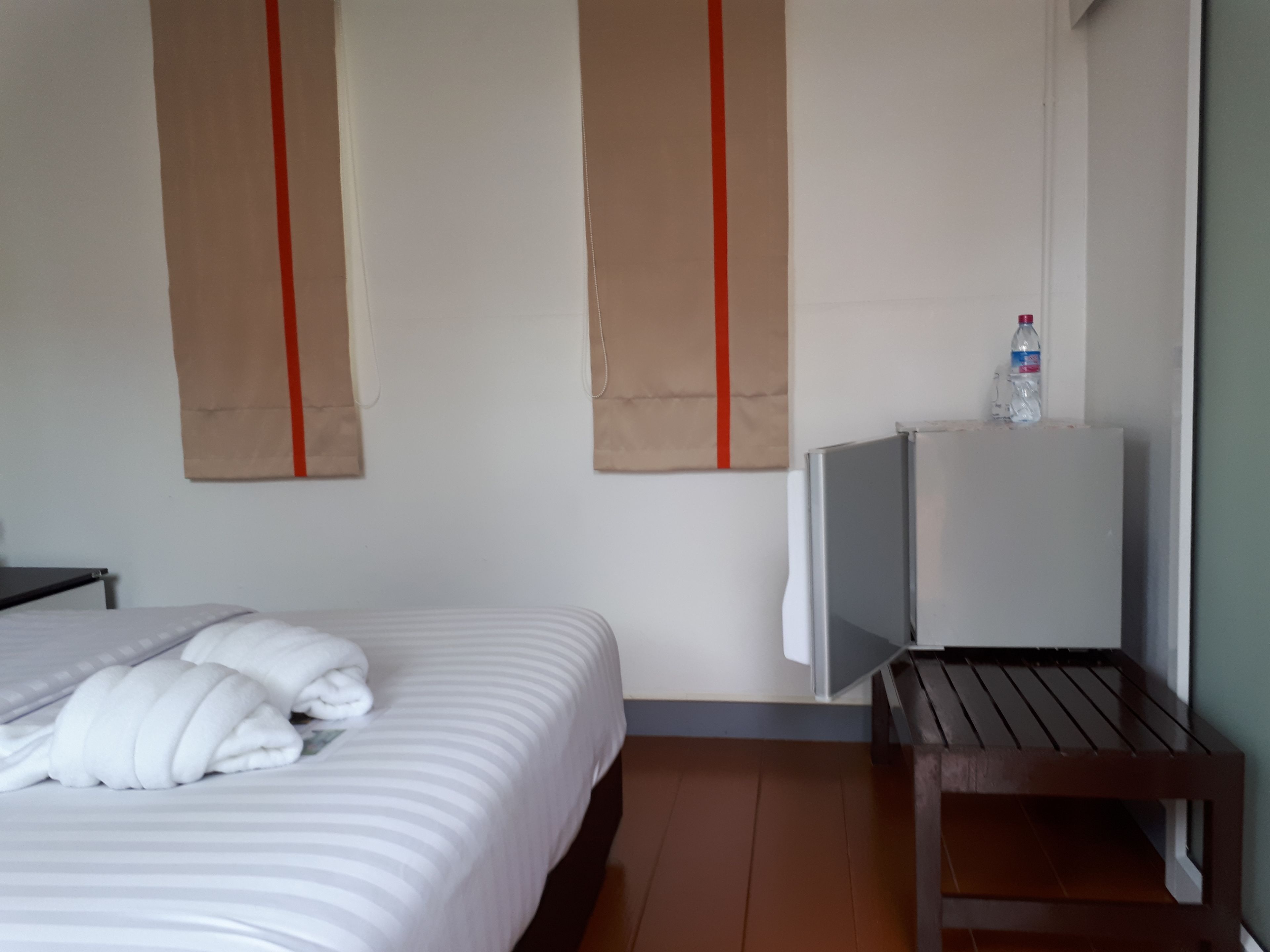 Een hotelkamer met een bed, een televisie op een standaard, en een fles water op de standaard.