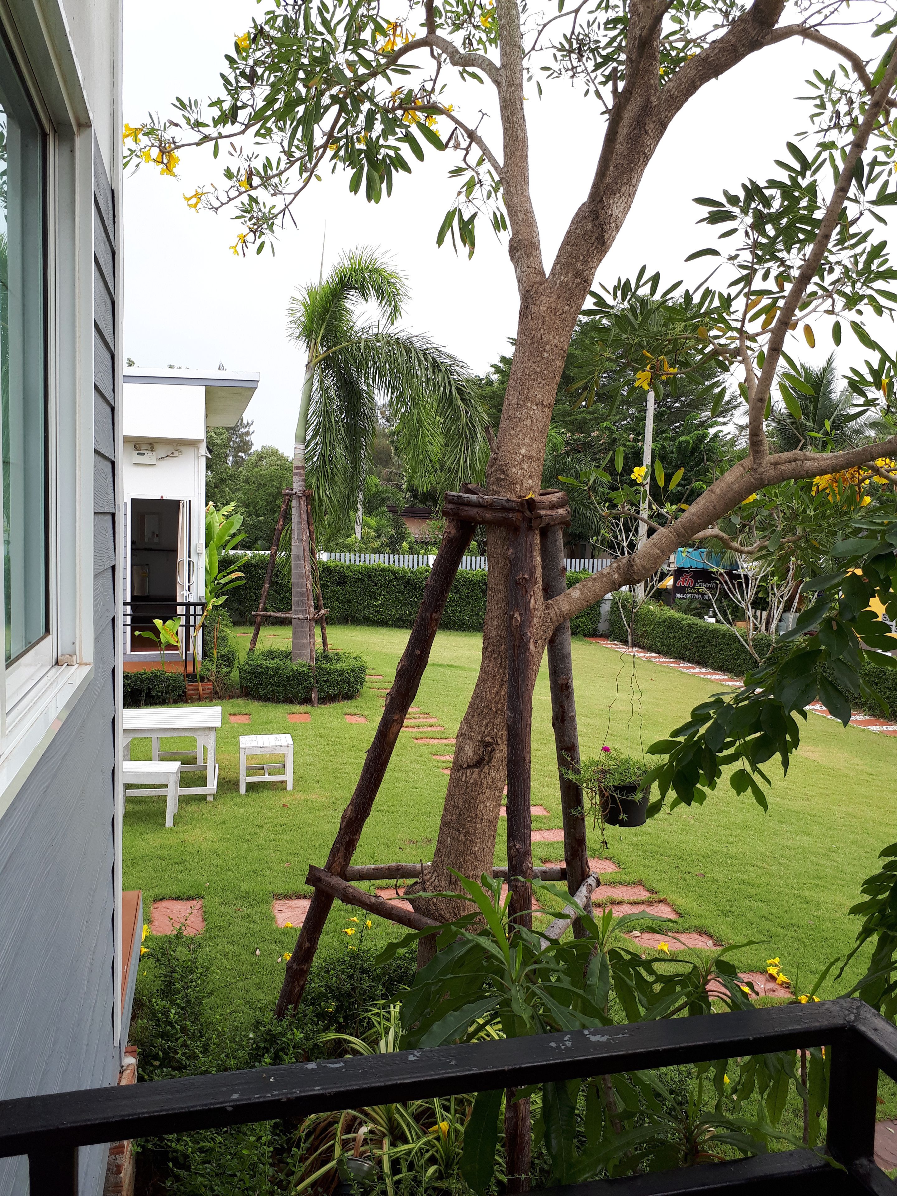 Un jardín con un árbol, un banco blanco y una pequeña mesa.