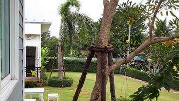 Un jardín con un árbol, un banco blanco y una pequeña mesa.