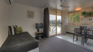 A compact room with a bed, a TV, a dining area, and a kitchen. - Maroochy River Bungalows (Diddillibah)