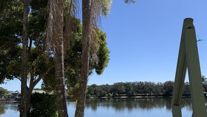 A view of a lake with palm trees and a wooden deck. - Maroochy River Bungalows (Diddillibah)