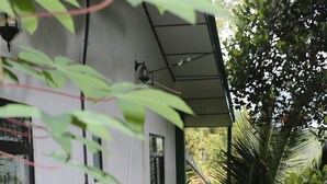 A white building with a white picket fence, surrounded by lush greenery and plants. - 9 Arch View Rest Inn (Ella)