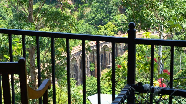 A balcony with a view of a stone bridge and lush greenery. - 9 Arch View Rest Inn (Ella)