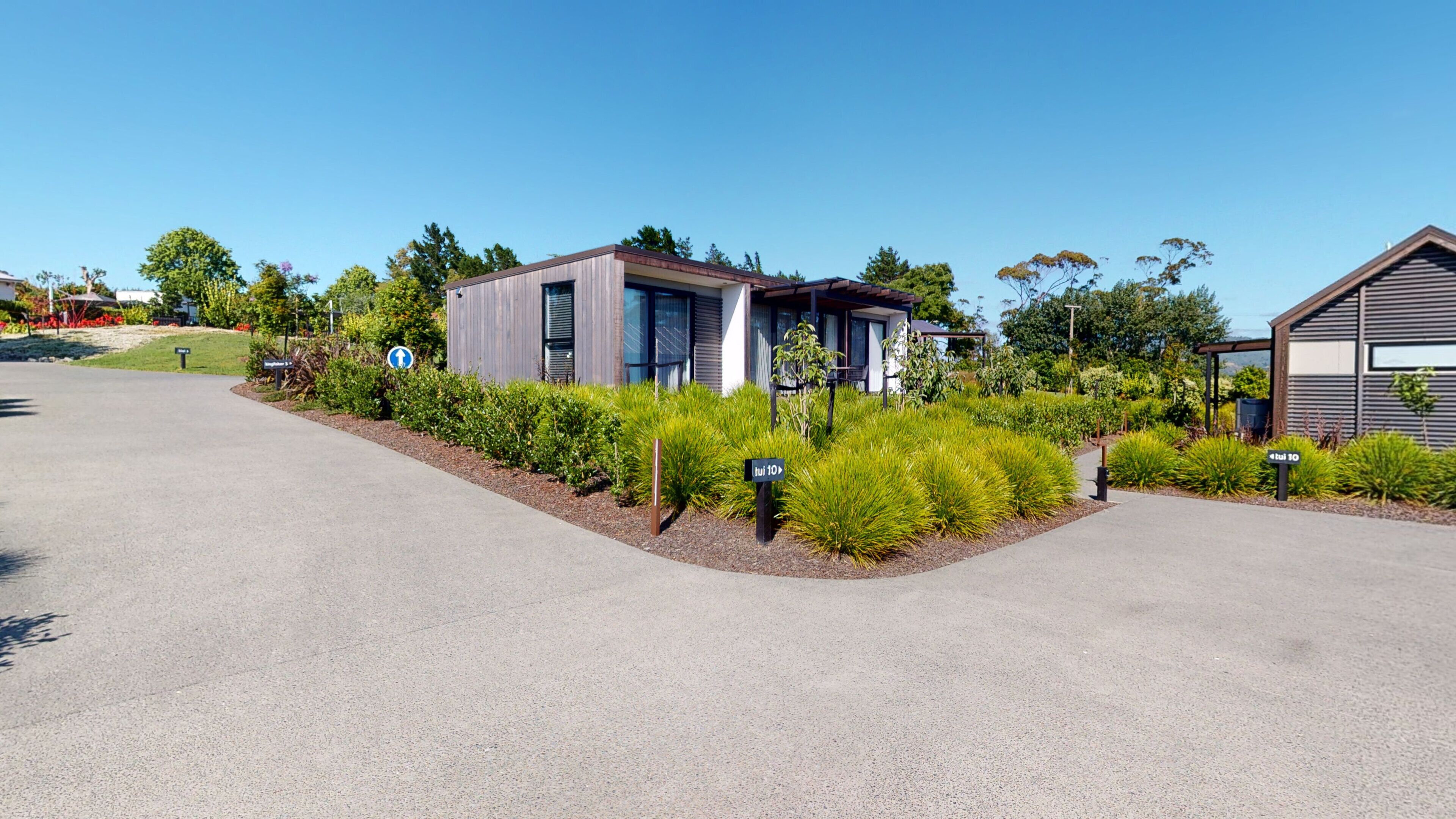 A modern residential area with two houses, well-maintained gardens, and a clear sky.