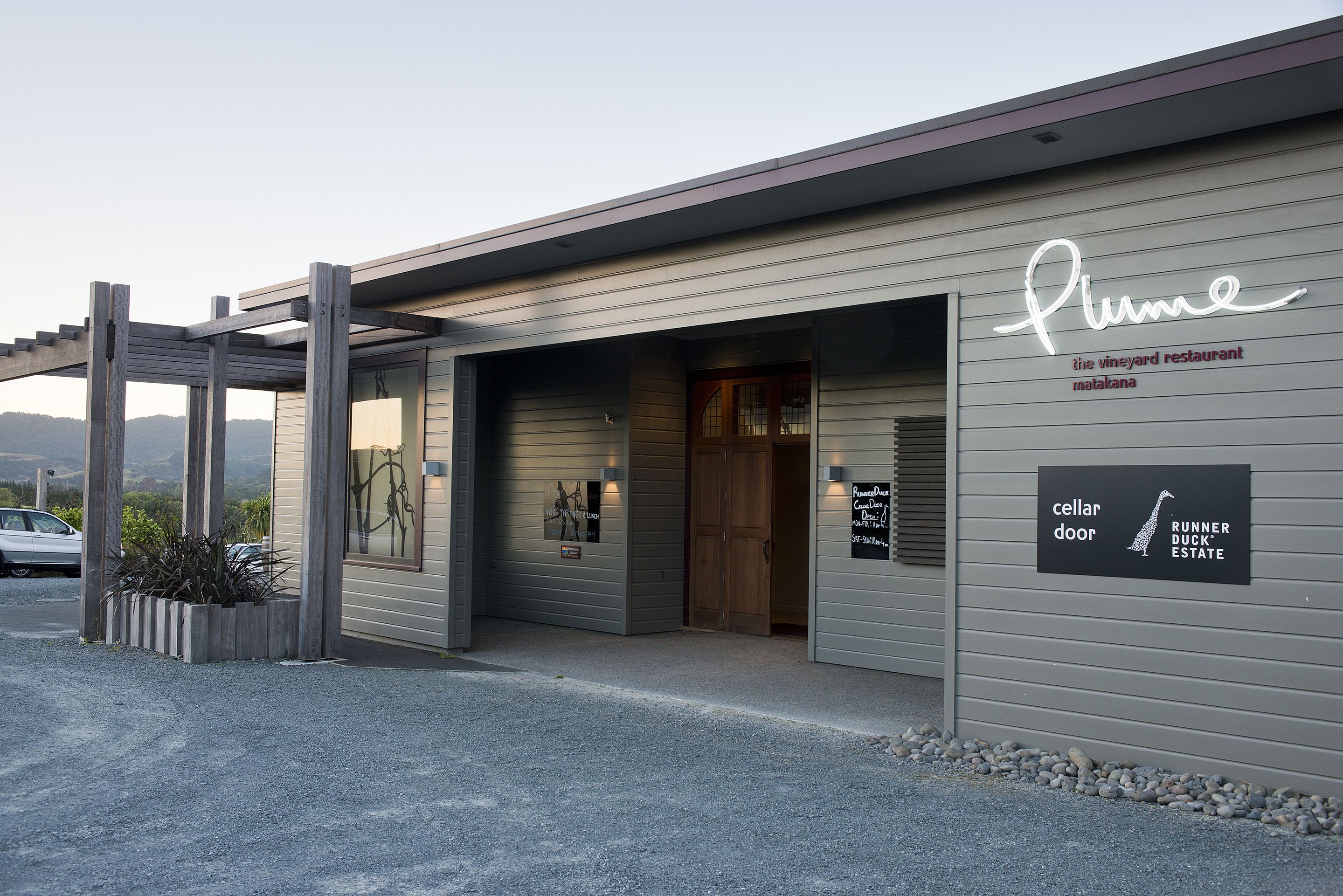 Un edificio moderno con un'insegna che riporta 'Plume the vineyard restaurant' e 'cellar door'.