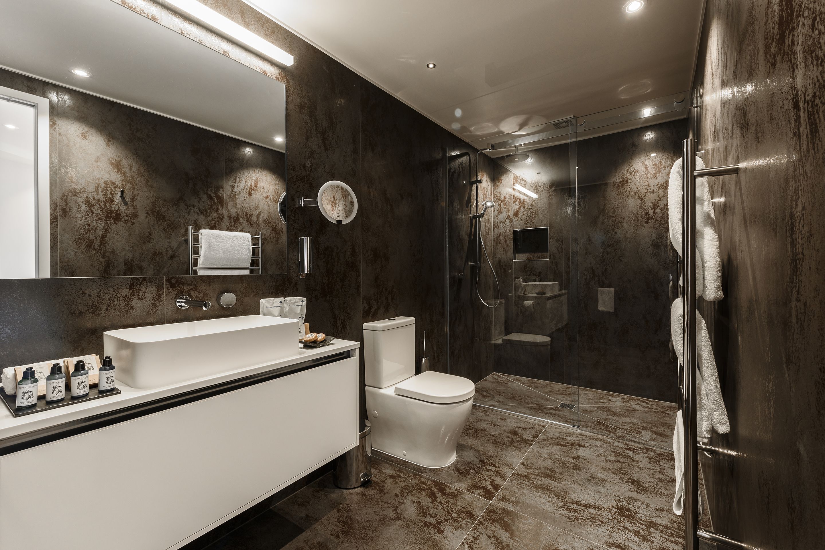 A modern bathroom with a white vanity, a toilet, and a glass-enclosed shower area.
