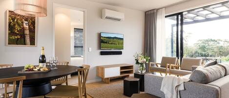 A modern living room with a dining area, a sofa, a TV, and a large window with a view.