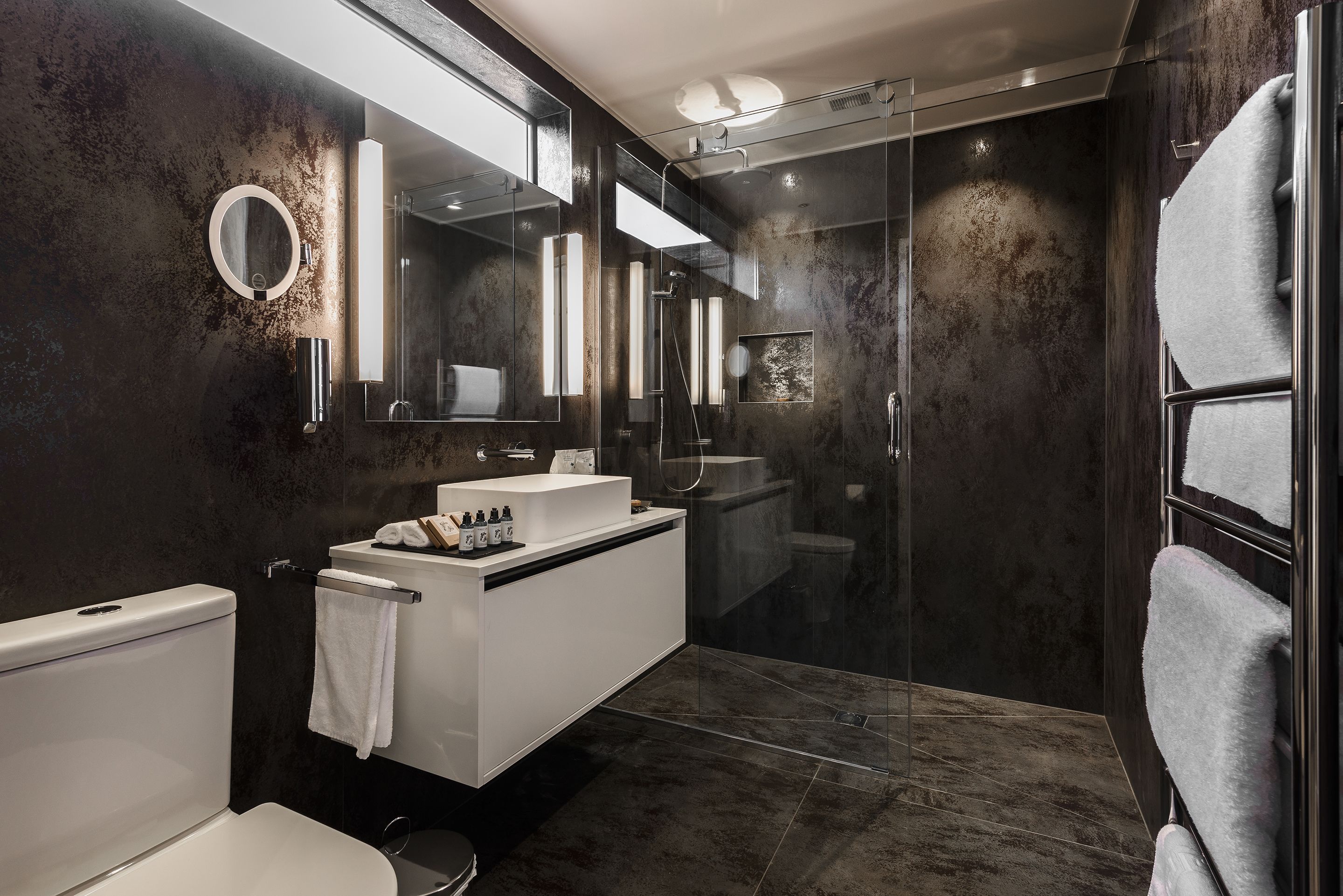 A modern bathroom with a glass-enclosed shower, a white sink, and a large mirror.
