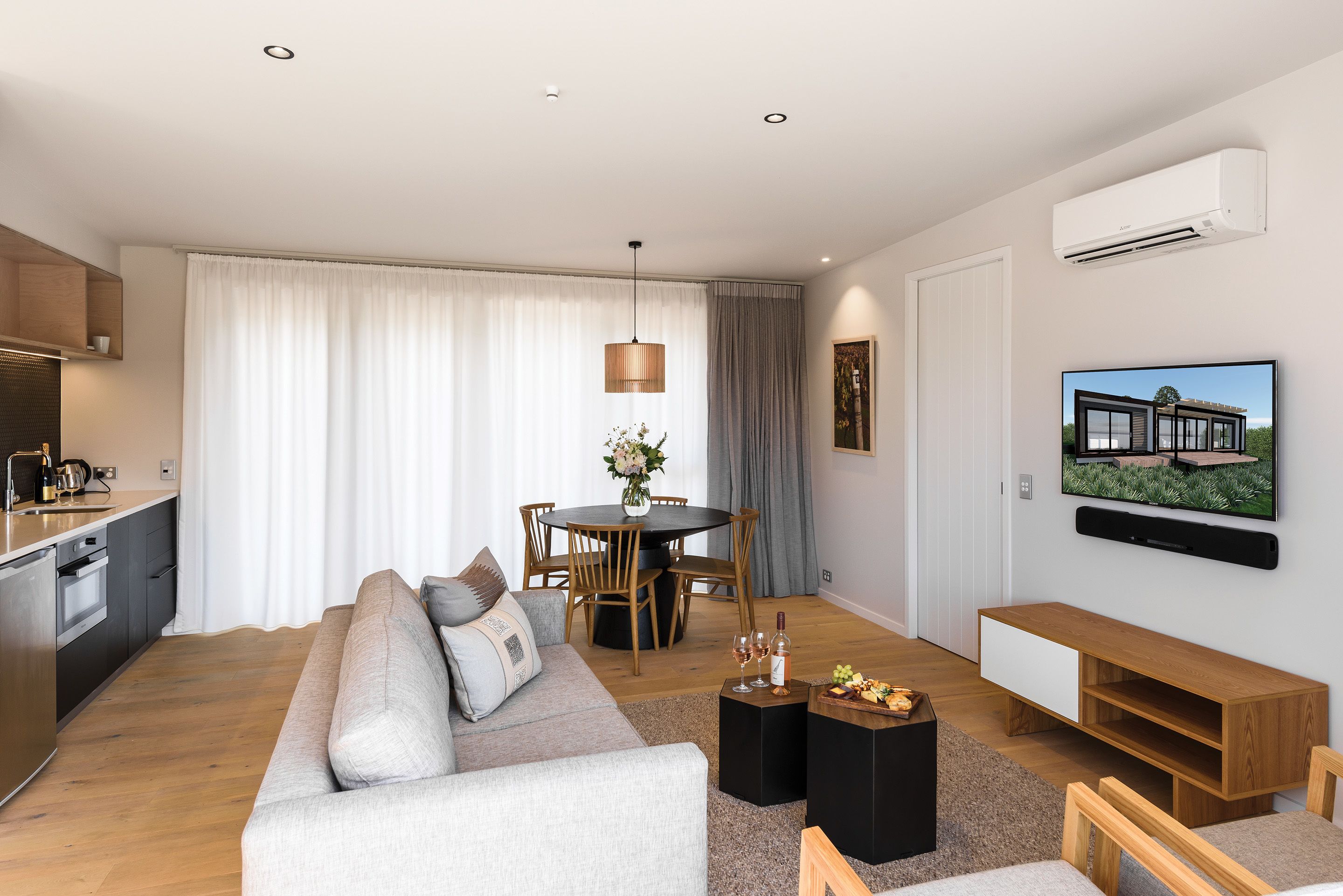 Ett modernt vardagsrum med en soffa, ett soffbord, en tv och en matplats med ett bord och stolar.