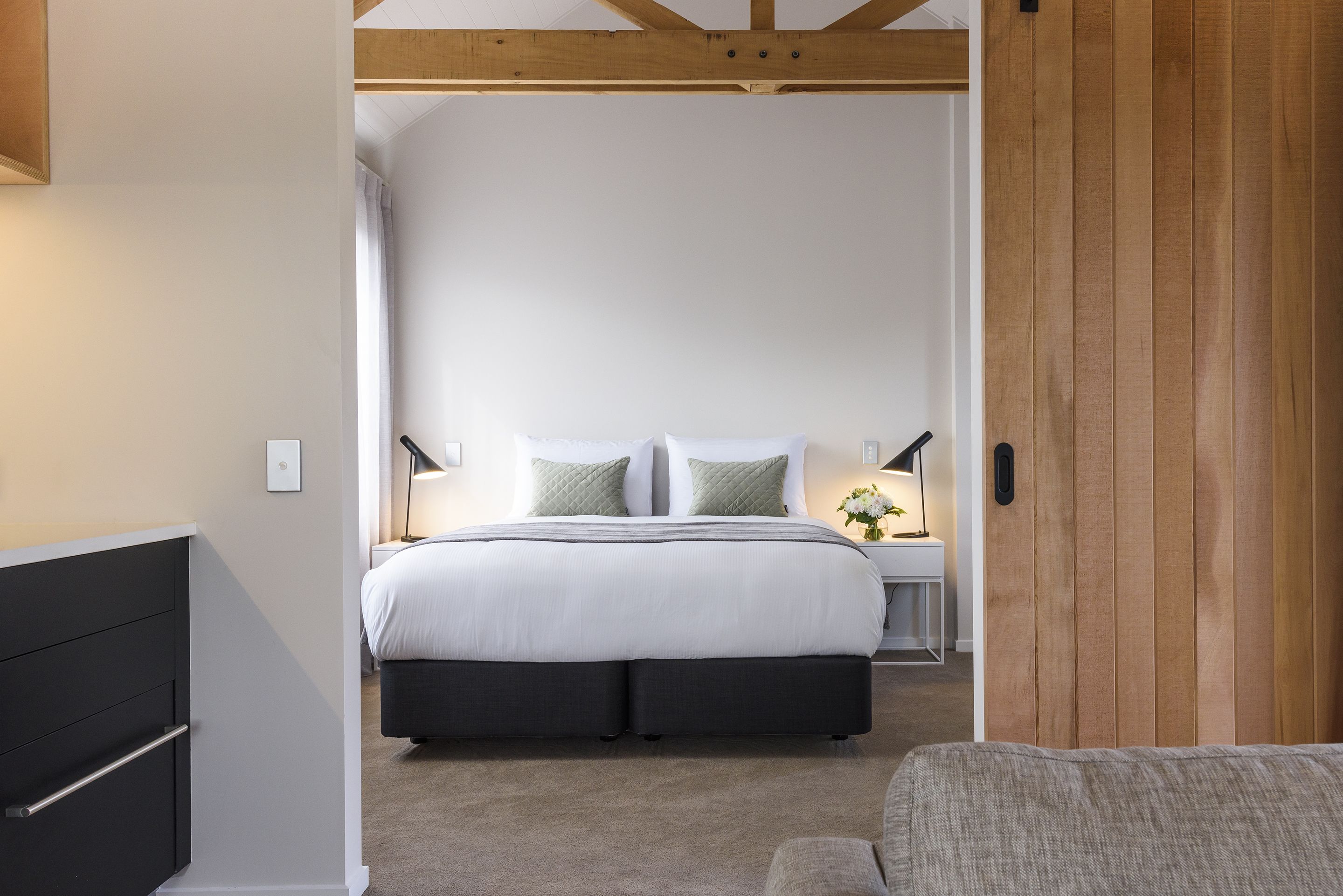 Un dormitorio con cama, mesitas de noche y una puerta de madera.