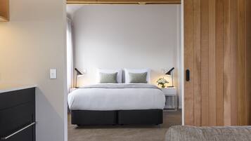 Un dormitorio con cama, mesitas de noche y una puerta de madera.