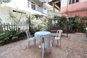 A courtyard with a round table and four chairs, surrounded by potted plants and a white fence. - Mama Mids Home (Morjim)