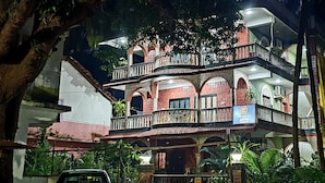 A multi-story building with balconies and arched windows, surrounded by greenery. - Mama Mids Home (Morjim)