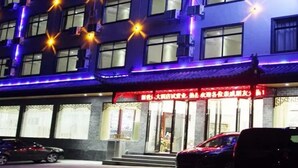 A multi-story building with illuminated windows and a red awning with Chinese characters. - Huangshan New Century Hotel (Huangshan)